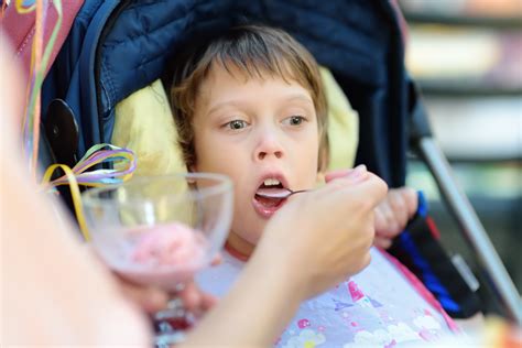 Niño con parálisis cerebral recibiendo alimentación asistida
